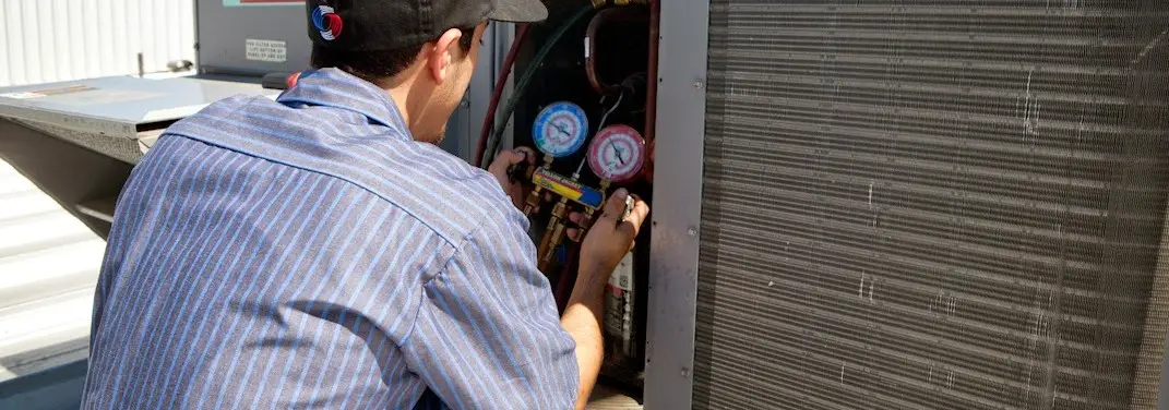 HVAC technician servicing a condenser unit in Ladue
